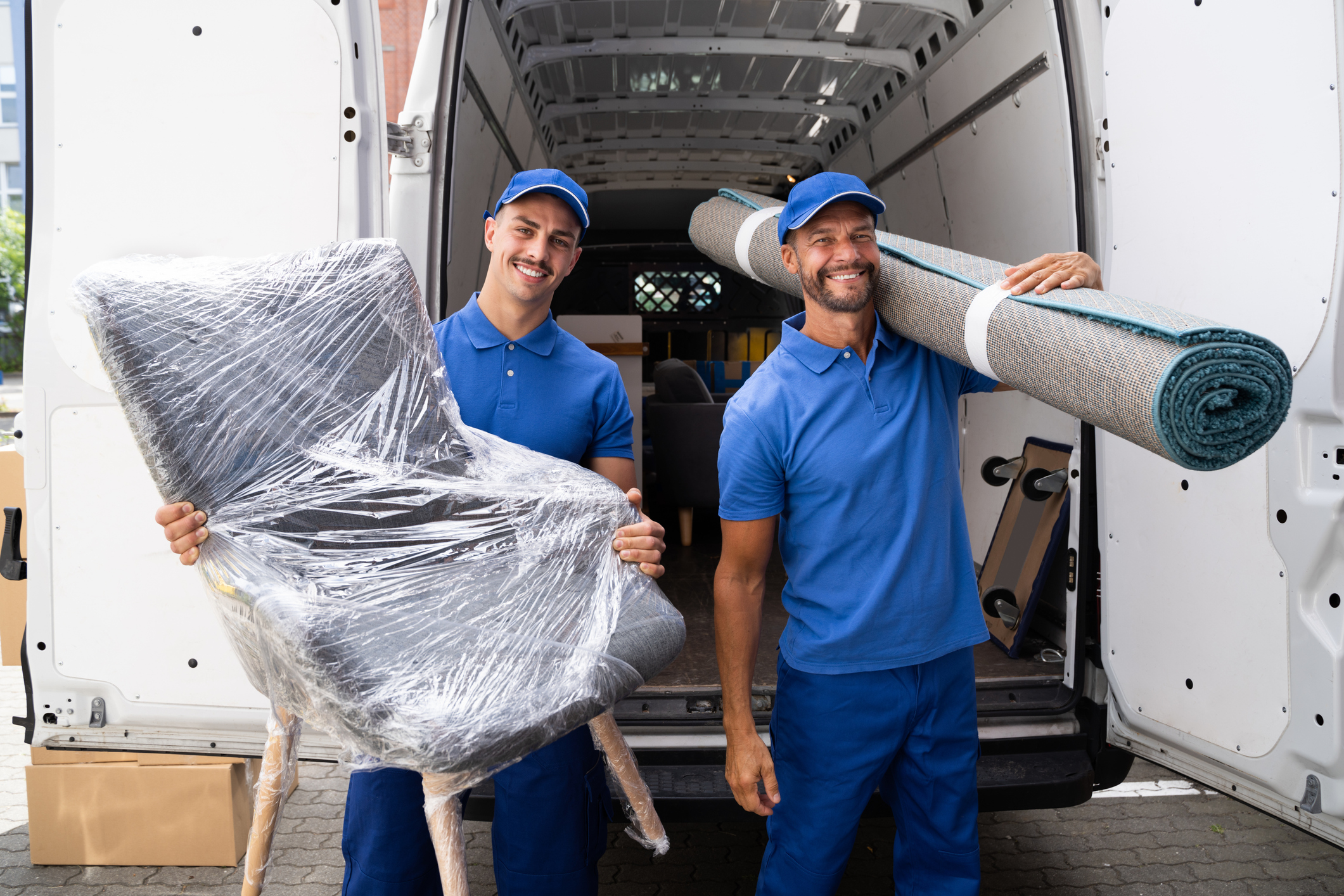 Umzugshelfer transportieren Möbel und Teppich aus Transporter