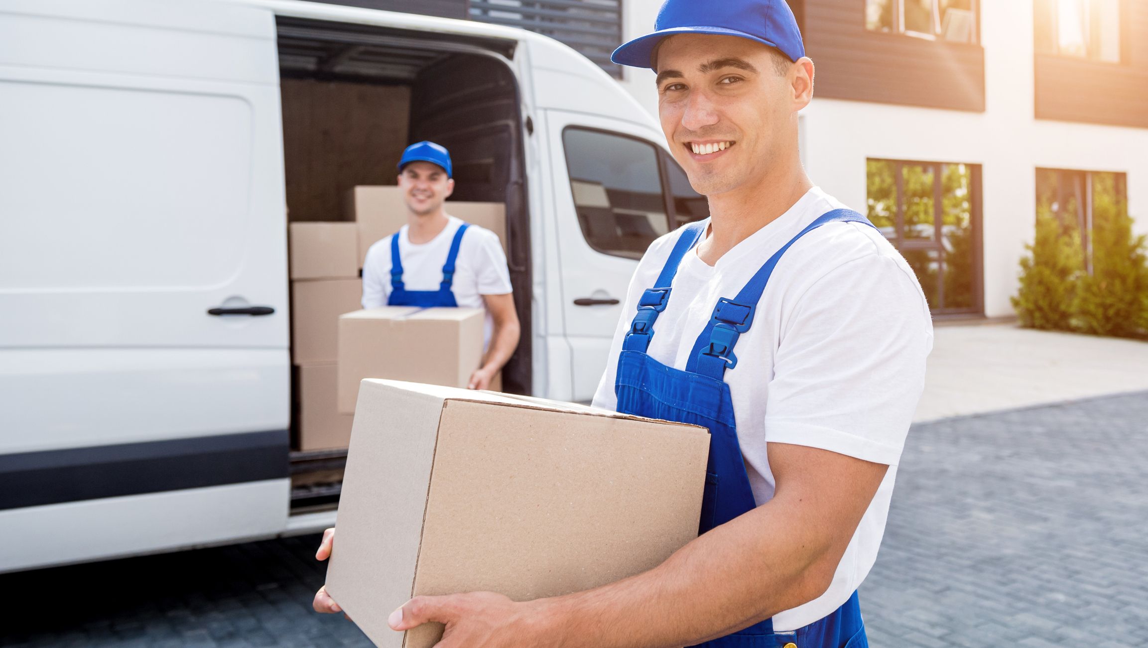 Umzugshelfer trägt Umzugskarton vor Transporter beim Wohnungsumzug